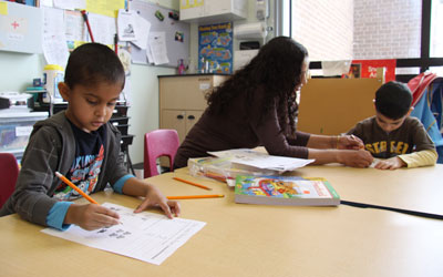 children doing homework with the help of a teacher