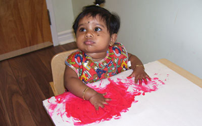 baby painting on paper with red paint