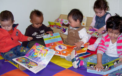 a group of small children looking at books